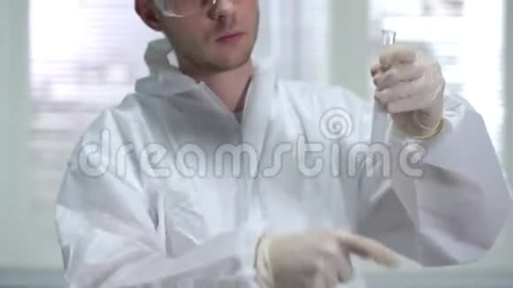 化学防护工作服摇管的年轻科学家在实验室里观察视频的预览图
