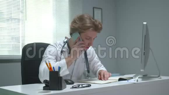 医生坐在医院的一张桌子旁打电话视频的预览图