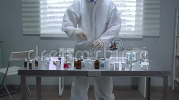 穿着防护服的人在实验室用棍子在管子里接触物质视频的预览图