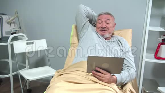 男人躺在医院的床上在药片上和别人说话视频的预览图