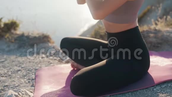 女人的一部分坐在垫子上在户外冥想慢动作视频的预览图