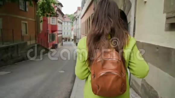 年轻的旅行女性穿着黄色外套背着背包走在美丽的德国老街上视频的预览图