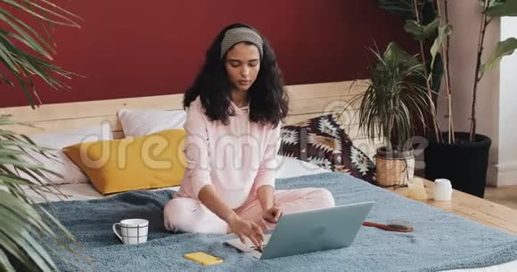 美丽的年轻非洲裔美国妇女在家做瑜伽运动在笔记本电脑上看教程视频的预览图