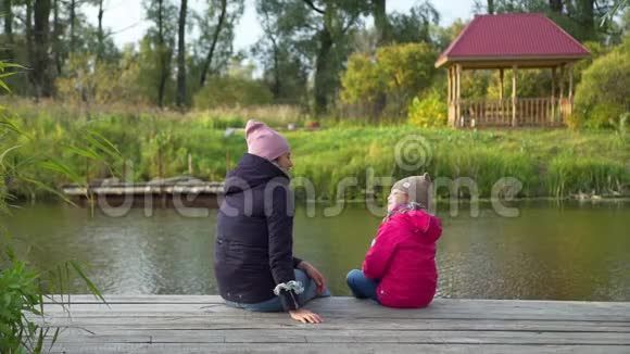 小女孩和她的母亲坐在码头上视频的预览图