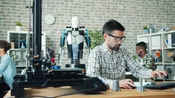 在办公室工作的女孩和男人用3d打印机和电脑制作机器人视频的预览图