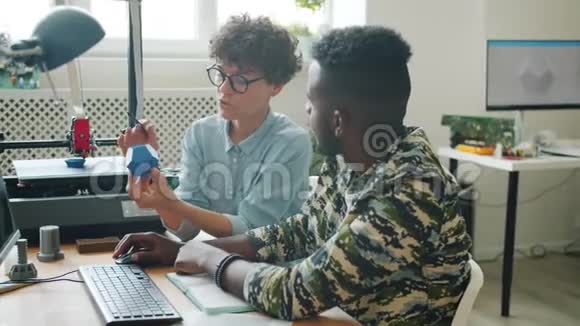 女人拿着3D打印机模型在办公室和男人用电脑说话视频的预览图