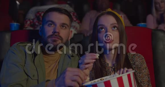 在电影院看电影时一对夫妇吃爆米花互相喂饭年轻的男人和女人视频的预览图