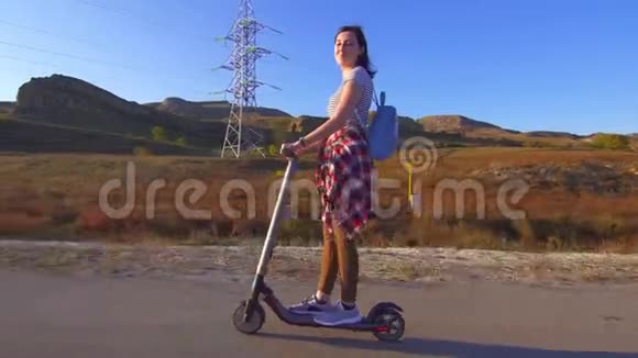 小女孩骑着电动滑板车在路上太阳视频的预览图