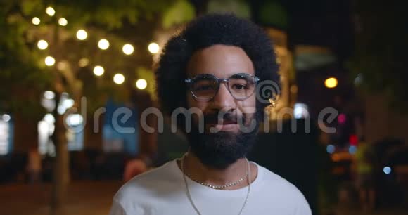 戴眼镜看镜头的英俊阿拉伯男人的肖像站在街边的30多岁大胡子男子近景视频的预览图