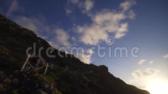 时髦的女孩在日落时走下悬崖从大西洋海岸下的陡峭楼梯降落到狂野的海滩视频的预览图