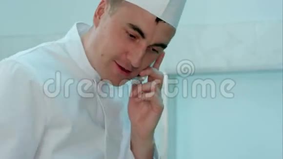 穿着白色制服的男厨师做饭和打电话视频的预览图