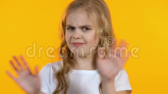 女孩皱着鼻子拒绝不健康的糖果黄色的背景视频的预览图