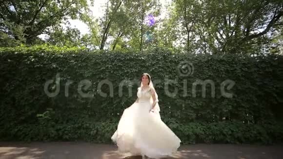 快乐的新娘在公园里旋转新娘礼服结婚纪念日视频的预览图