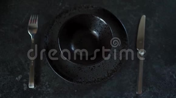 女人手把两个五颜六色的复活节彩蛋放在一个黑色的空盘子里放在黑暗的背景上关门视频的预览图