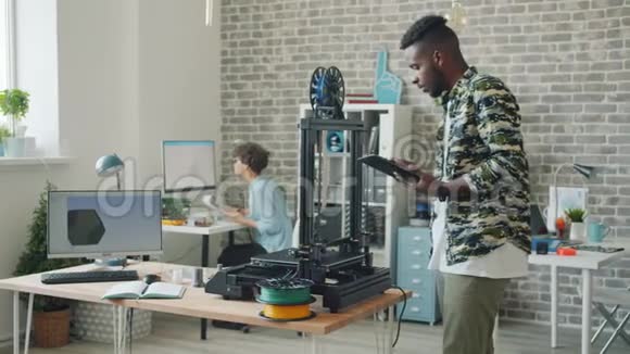 利用平板电脑打印3D机器人的年轻人在办公室工作享受工作视频的预览图