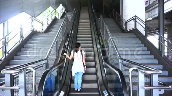乘坐公共交通自动扶梯背着背包的亚洲旅行者视频的预览图