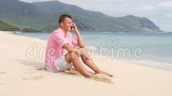 有智能手机的男人坐在沙滩上视频的预览图