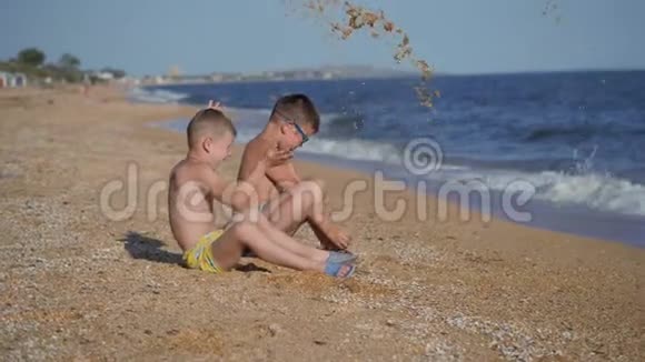 和孩子们一起在海上休息男孩们用沙子扔出一个贝壳孩子的情绪孩子们扔沙子视频的预览图