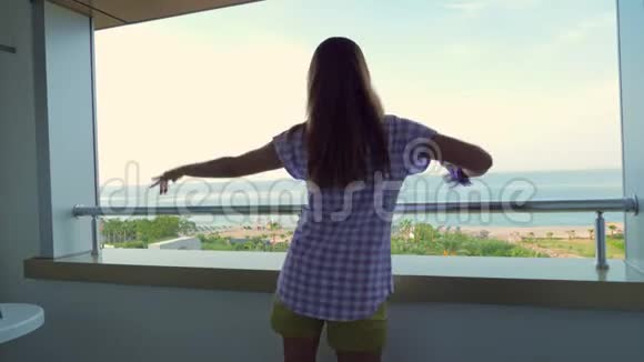 女孩在酒店的阳台上跳舞俯瞰大海或海洋视频的预览图