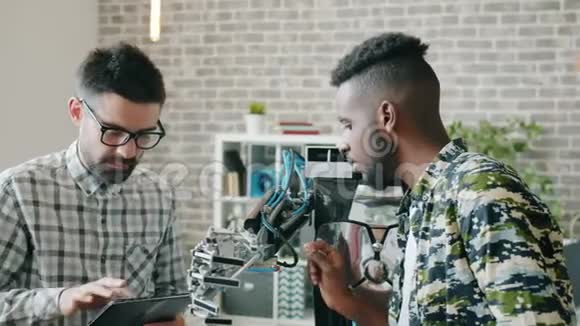 英俊的年轻人在办公室里一起用平板电脑测试机器人视频的预览图