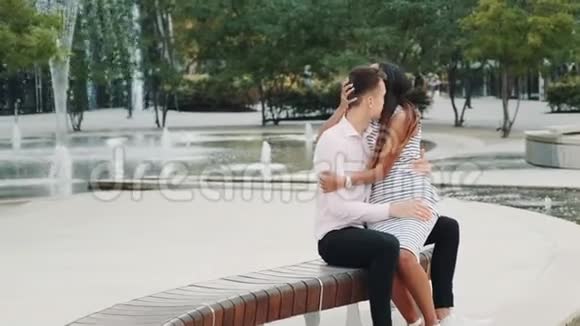 混血男女恋爱坐在公园的长凳上拥抱和交谈视频的预览图