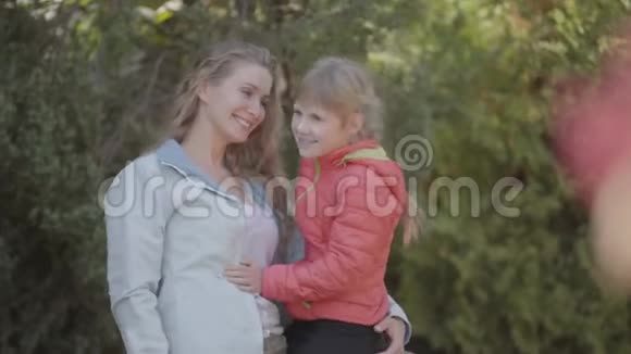 年轻的金发母亲手牵着她可爱的小女儿在公园里白种人女人在秋天晚上和视频的预览图