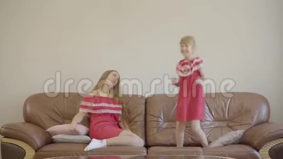疲惫的年轻女子看着跳在马车上的小可爱妈妈和女儿穿着同样的红色衣服视频的预览图