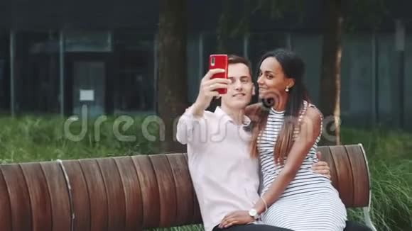 一对快乐的年轻夫妇在户外的长椅上自拍视频的预览图