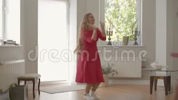 快乐的金发白种人母亲和小女儿穿着同样的衣服在家里玩耍旋转和跳舞视频的预览图