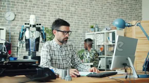 在办公室工作的男性使用电脑和制造3d打印机机器人的细节视频的预览图