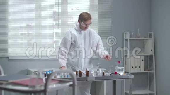 穿防护工作服的人在实验室检查化学试管视频的预览图