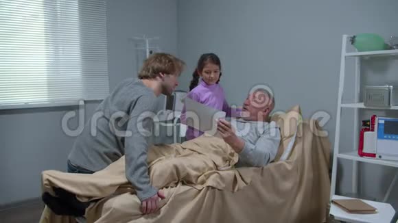 男孩和女孩和躺在床上的祖父交谈视频的预览图
