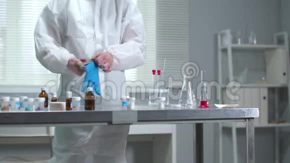 戴防护工作服的人在实验室戴医疗手套视频的预览图