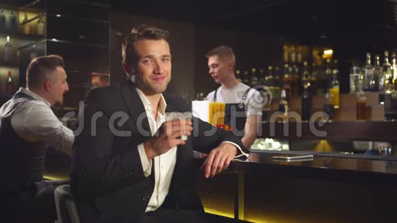 慢动作男人在酒吧喝酒微笑着看着镜头视频的预览图