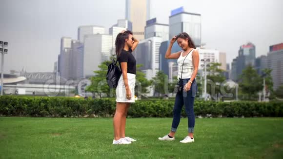 两个年轻的女人在公园里谈论着绿草和周围的建筑物视频的预览图