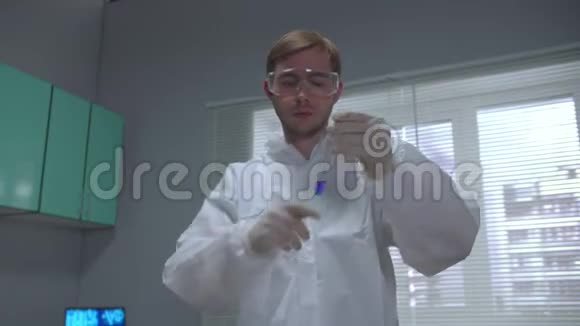 实验室用蓝色液体在保护性工作服摇摇管中的化验师视频的预览图