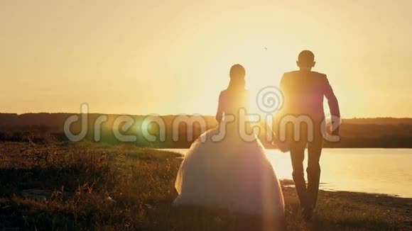 新娘和新郎穿过田野在夕阳下迎接太阳视频的预览图