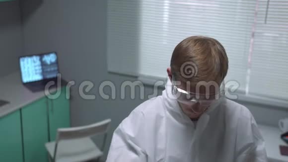 化验员穿着保护工作服拿着带液体的管子在实验室里看起来不赞成视频的预览图