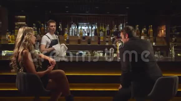 穿西装的男人和女人说话在酒吧给她一杯鸡尾酒视频的预览图
