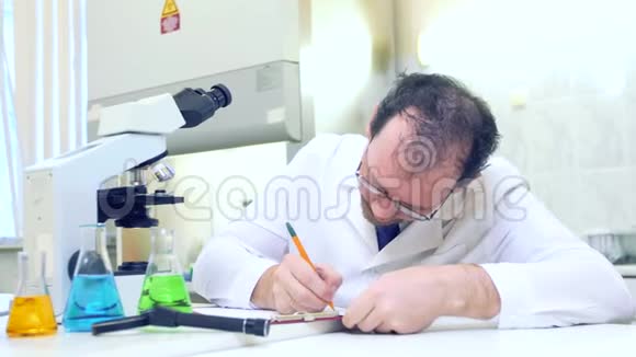 化学家疯了一个疯狂的科学家在一个科学实验室进行实验用显微镜进行研究视频的预览图