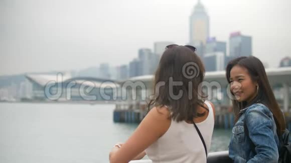 两个迷人的女孩在码头边谈论水和周围4K的建筑视频的预览图