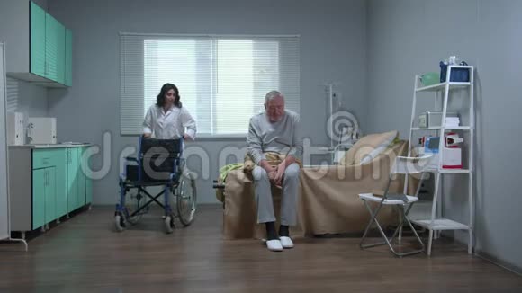 医生帮助老病人坐在医院的轮椅上视频的预览图