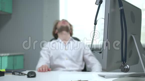 医生坐在一张桌子旁睡在听诊器的背景上视频的预览图