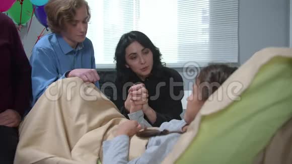 男孩坐着女人牵着躺在医院床上的女孩的手视频的预览图