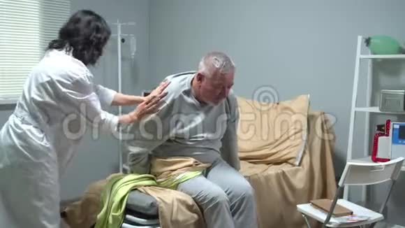 医生帮助老人坐在医院的轮椅上视频的预览图
