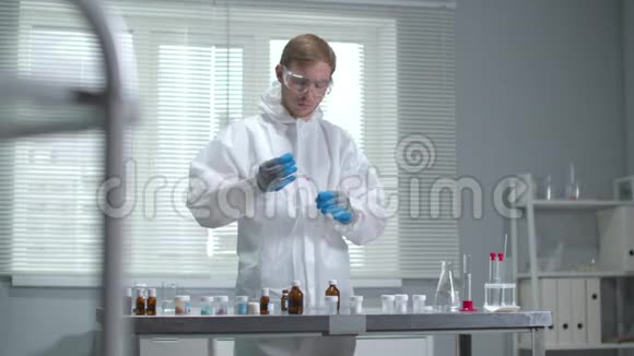 戴防护工作服和手套的人在实验室里处理化学品视频的预览图