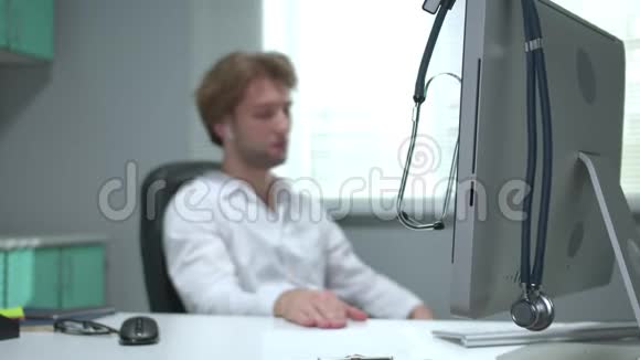 医生闭着眼睛坐在桌子旁戴着耳机听音乐视频的预览图