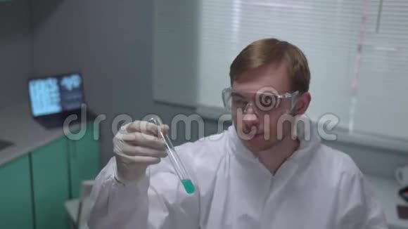 防护工作服的化验员用带绿色液体的试管在实验室微笑视频的预览图