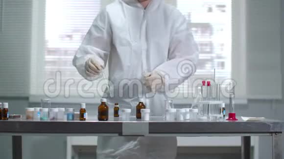 戴防护工作服和手套的年轻科学家在实验室里处理化学品视频的预览图