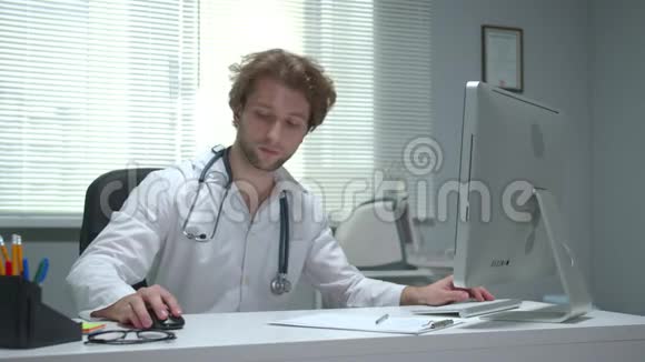 医生坐在医院的一张桌子旁用键盘打字视频的预览图